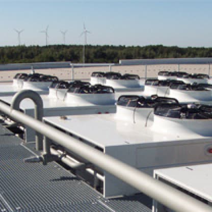 Rooftop condensers on a CHP plant with wind turbines behind